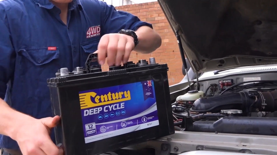 Mechanic installing a Century deep cycle battery in a vehicle