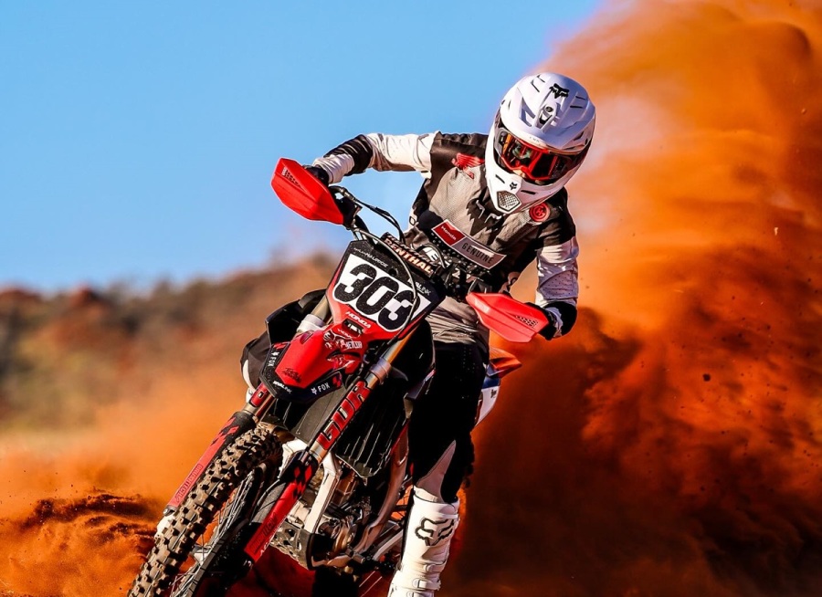 a person riding a powerful dirt bike through sand with beautiful graphics kits